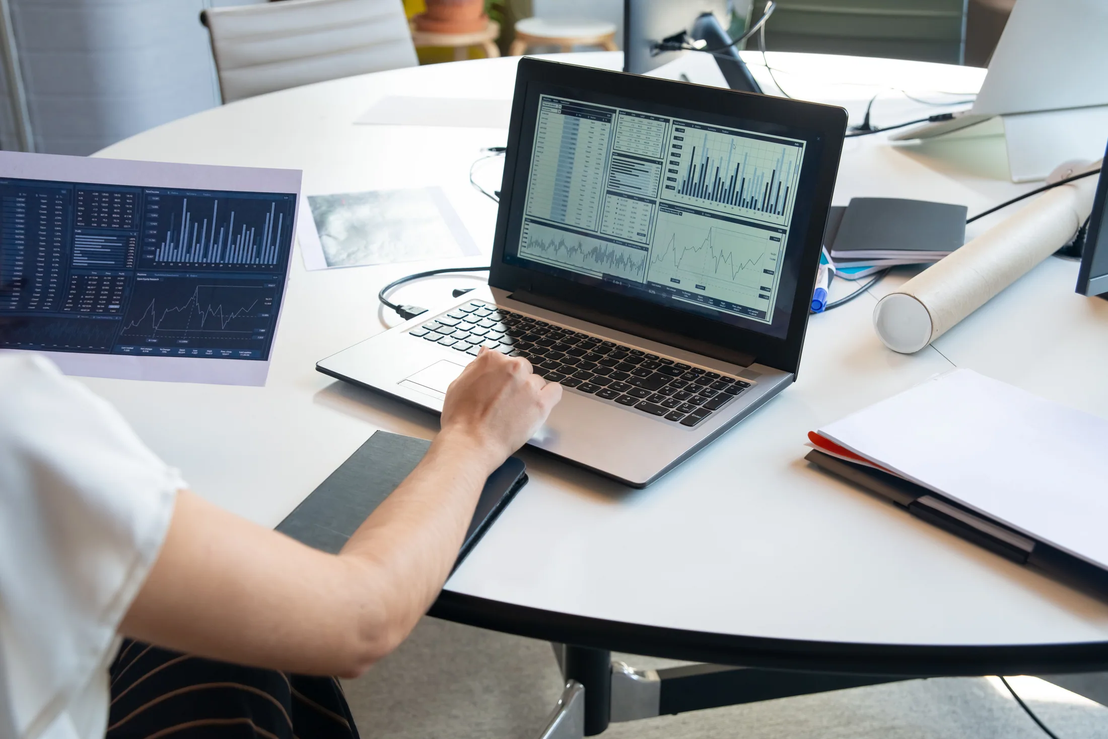 An analyst cross-checking a printed financial report against data on a laptop